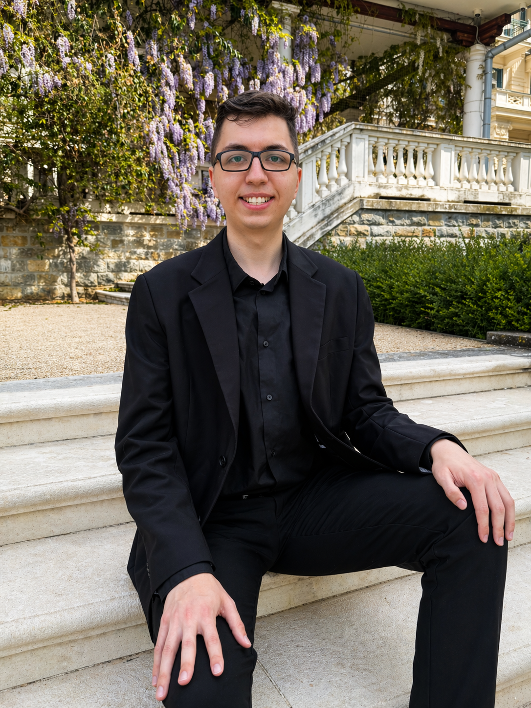 Alex Hren seduto all’aperto sotto un glicine in fiore